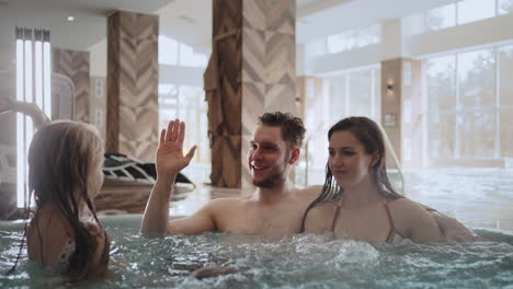 spouses-are-relaxing-in-jacuzzi-in-modern-spa-center-children-are-playing-near-happy-family-weekend